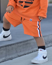 kids orange sweat shorts with black and white side stripes